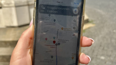 Handy in der Hand mit Hintergrund einer Altstadt