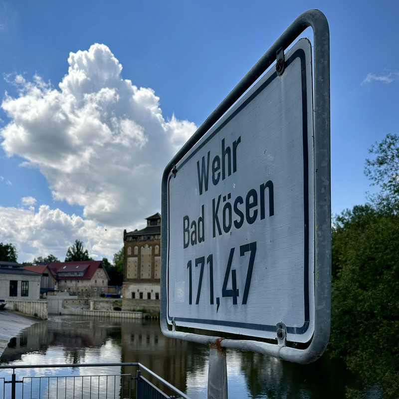 Schil mit Wehrdaten und im Hintergrund der Fluss